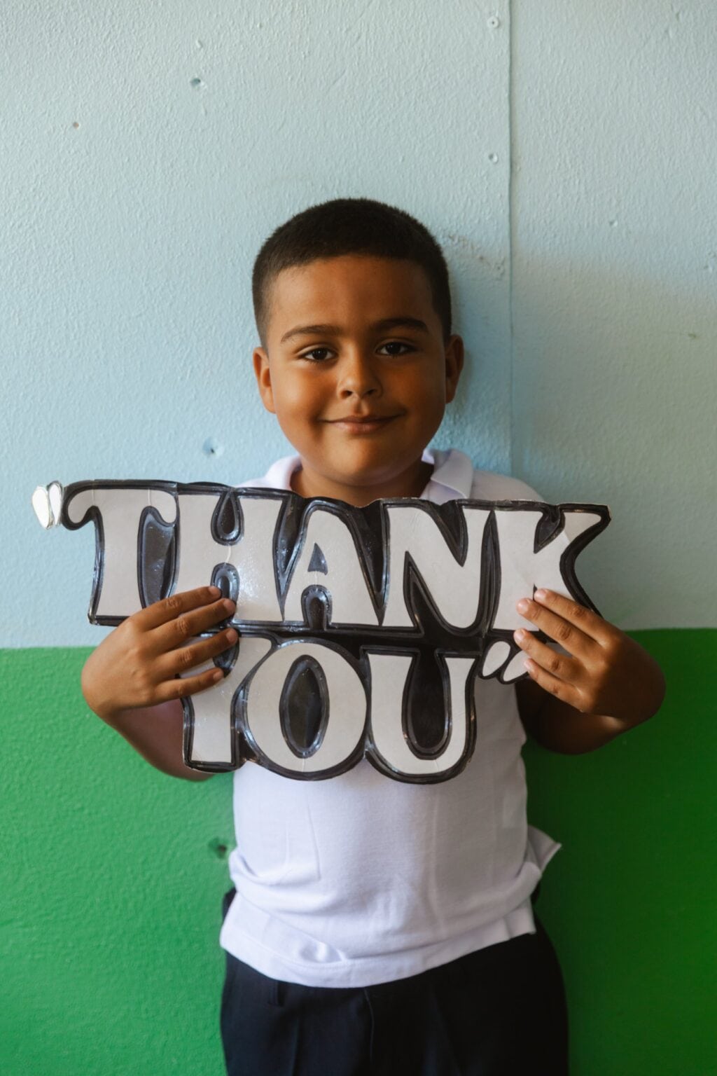 A smiling boy holding a thank you sign